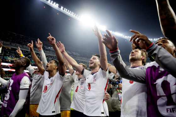 England players celebrate, hands raised in the air, on the soccer field