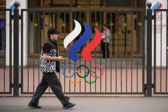 A man walks past a fence with Olympic Rings in front of the Russian National Olympic Committee building in Moscow.