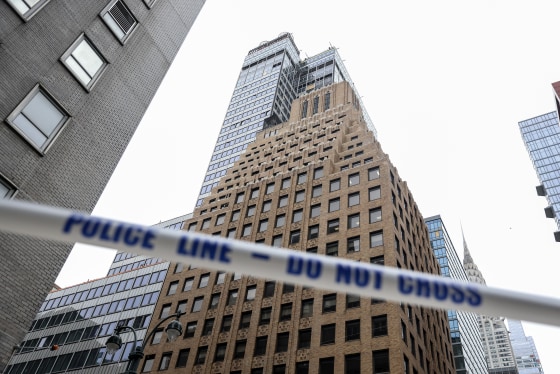 White tape with blue lettering reading POLICE LINE - DO NOT CROSS stretched in front of high-rise buildings in downtown Manhattan.