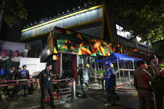 Emergency responders outside a nightclub with signs of a fire on its facade.
