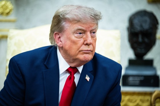 Donald Trump looks off while seated in a chair in the Oval Office