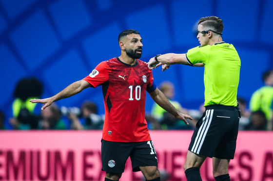 Referee Francois Letexier talks with Mohamed Salah on the soccer field, Salah's arms are outstretched as Letexier points at him