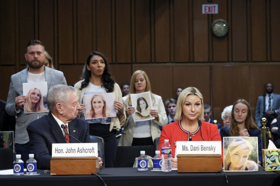 Epstein survivors and family members stand behind former Attorney General John Ashcroft and Dani Bensky.