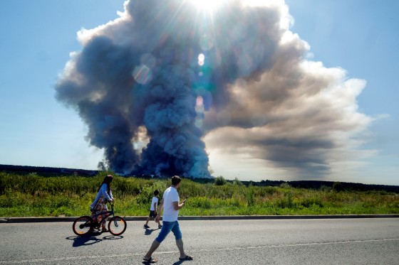 Local residents walk past the smoke of a fire at the Russian e-commerce firm Wildberries' logistics complexes.