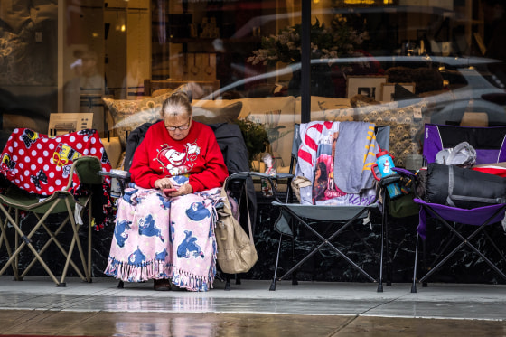 A woman looks at her phone on Colorado Boulevard on Dec. 31, 2025 in Pasadena, Calif.