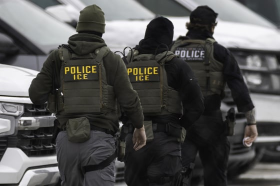ICE agents walk in line.