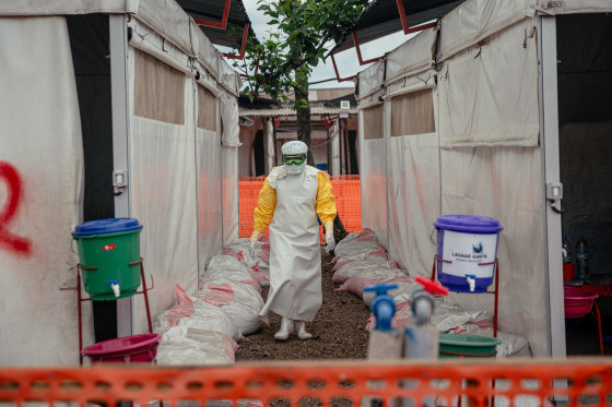 A Doctors Without Borders (MSF) doctor wearing personal protective equipment moves through the isolated red zone to monitor patients.