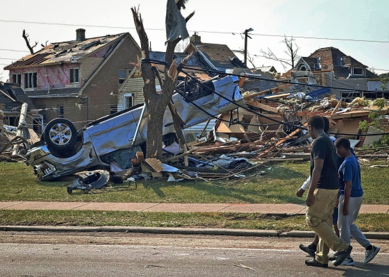 People walk past damaged homes Tuesday in Menasha, Wis., the day after a tornado tore through the area.