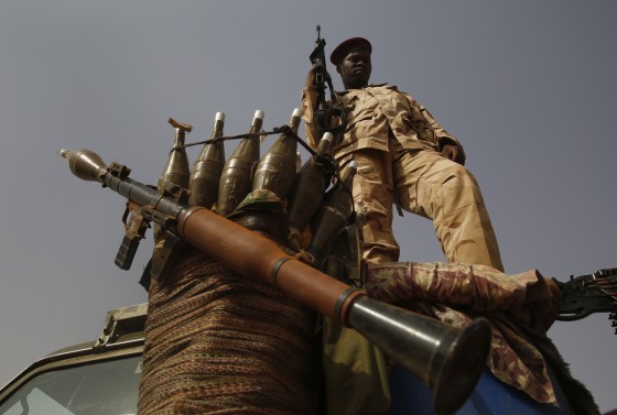 A Sudanese soldier from the Rapid Support Forces stands on a vehicle while holding a weapon.
