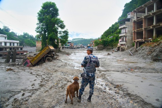 A polic officerwith a sniffer dog looks at the damage in the aftermath of flash floods in Devighat in the Nuwakot district in Nepal, on Aug 27, 2026.