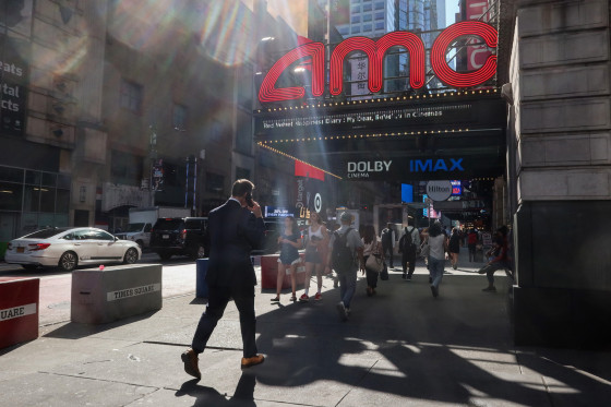 People walking past an AMC Movie Theater in Times Square in New York City.