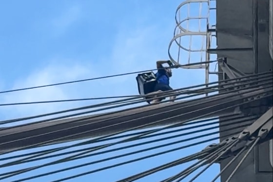 Galymzhan Abaildayev scales a bridge, seen from underneath the bridge wires