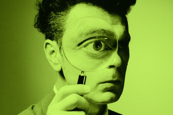 A man holding a magnifying glass to his eye.