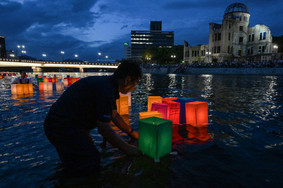 People push colorful paper lanterns out onto the Motoyasu River in Hiroshima.