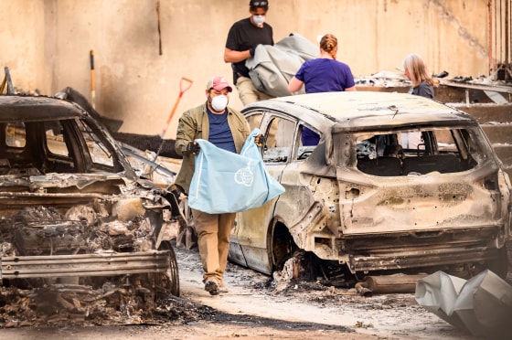 Residents carry the remains of deceased dogs at a home burned in the Old Trails fire in Spokane, Wash., on Aug. 4, 2026.