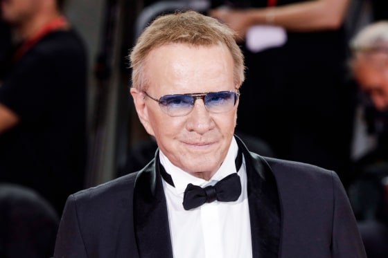 Christopher Lambert stands for a portrait wearing sunglasses, a black suit and black bowtie