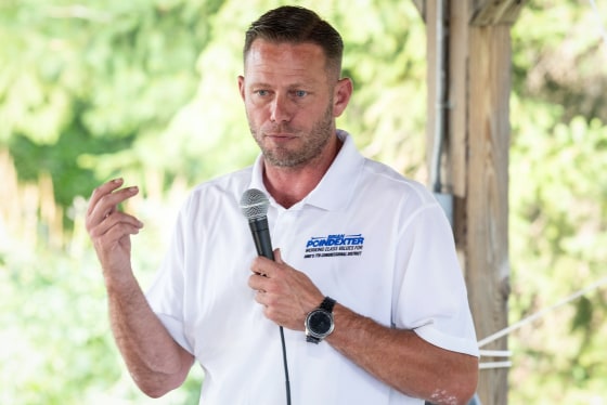 Brian Poindexter speaks into a microphone he's holding while standing outside