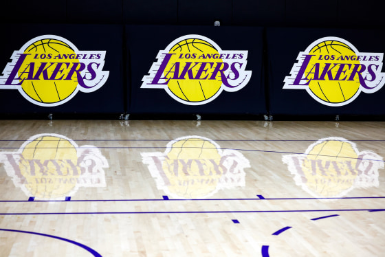 The Los Angeles Lakers logo, printed three times on the wall, appears on the basketball court with reflections on the floor