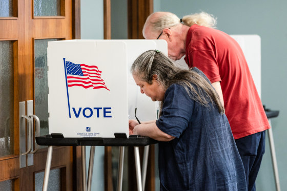 People vote at voting booths inside of a room