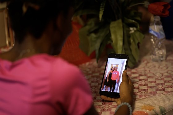 Image: Maggie looking at her phone with a photo of her and her father.