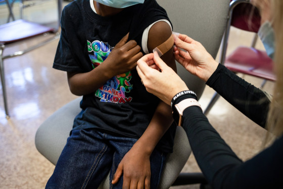 A healthcare worker puts a band-aid on a child's arm