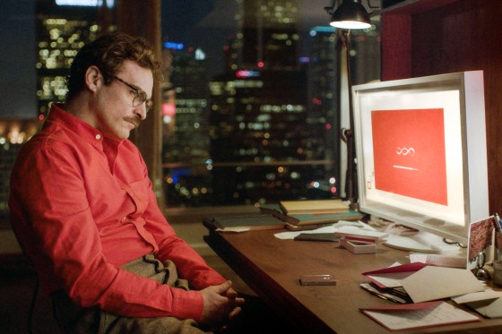 Joaquin Phoenix sits at a computer desk and looks at a loading screen on a computer screen
