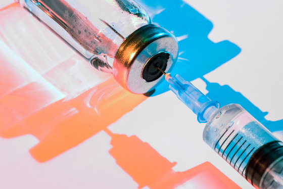 Glass bottle with vaccine and syringe for injection.