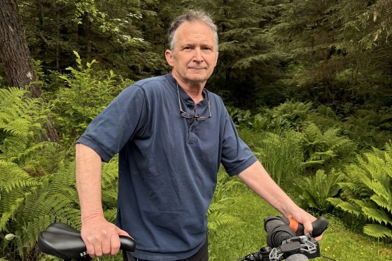 Image: Dan J. Sullivan in front of a forest, holding his bike