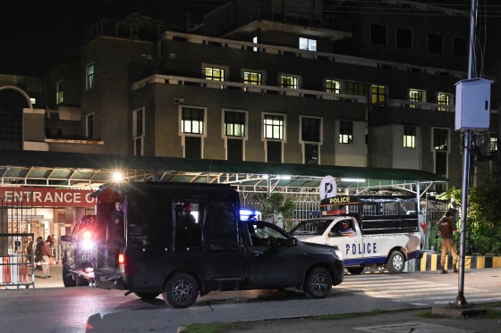 Two law enforcement vehicles parked in front of a hospital building at night.