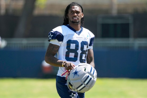 Ceedee Lamb holds his football helmet while walking on the field in uniform
