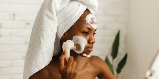 woman applying facial cleanser with a brush