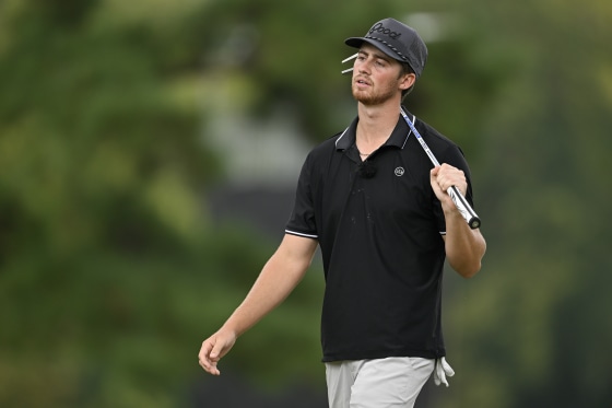 Garrett Clark walks with a golf club over his shoulder.