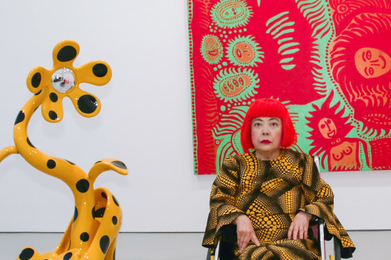 Yayoi Kusama next to her colorful and abstract art work.