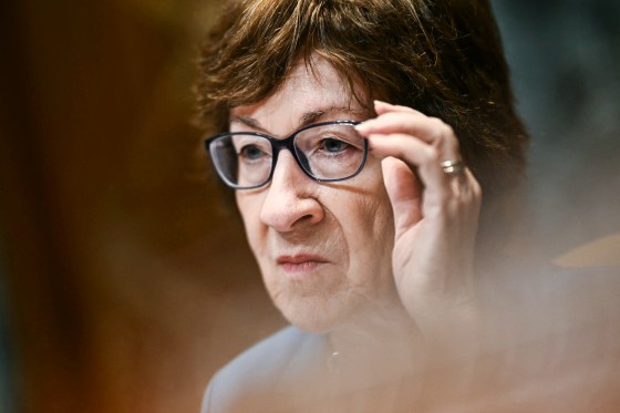 Susan Collins adjusts her glasses while seated