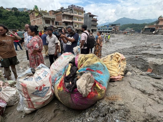 Residents stand next to piles of belongings in Trushuli, Nepal, on Saturday, four days after devastating floods swept through the region, killing hundreds.