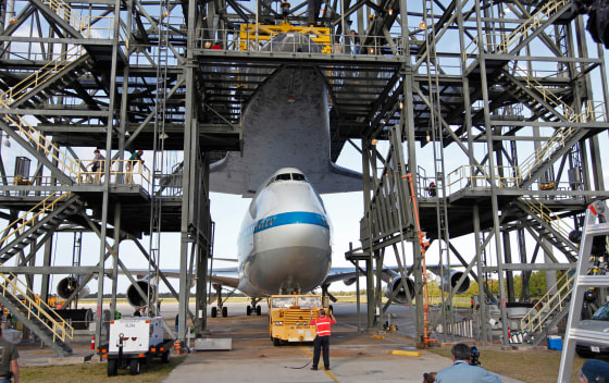 Space center workers watch as the space shuttle Discovery (above) is approached by a NASA 747 aircraft, which was towed into the Mate Demate facility at Kennedy Space Center in Cape Canaveral, Fla., April 15.