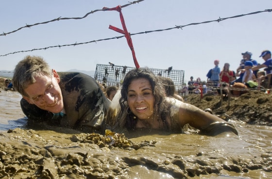 Sandra Parker and Andrew Keith crawl through the mud during the Gladiator Rock N' Run, April 28, at the Great Park in Irvine, Calif.