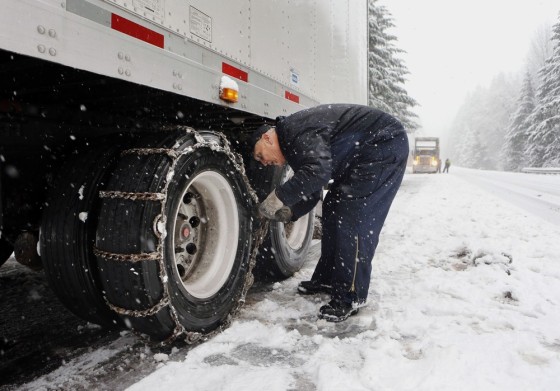 Del Queener of Puyallup, Wash., puts chains on his semitruck trailer tires as he prepares to drive over Oregon's Willamette Pass during a snow storm Monday.