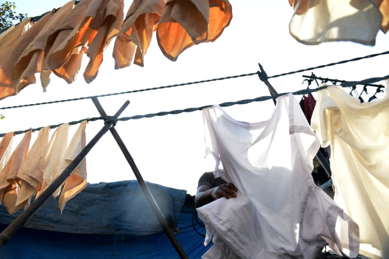 A man hangs clean clothes to dry at an open air laundry facility.
