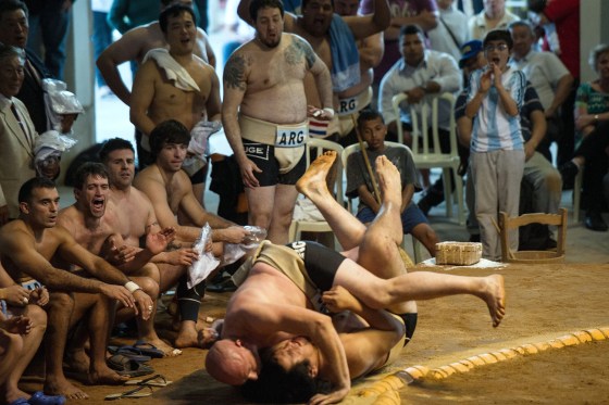 Sumo wrestlers fall outside the ring during the Sumo wrestling South American Championship on July 22.