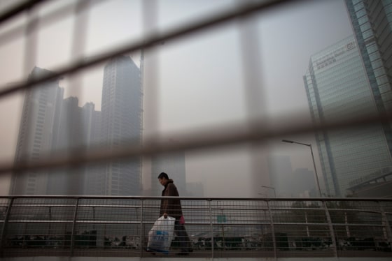In this file image from 2010, a man walks on a pedestrian overpass on a hazy day at Beijing's Central Business District.