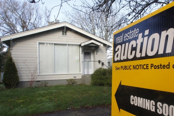 In this Feb. 23, 2012, photo shows a auction sign in front of a home, in Salem, Ore. Home prices fell in December for a fourth straight month in most major U.S. cities, as modest sales gains in the depressed housing market have yet to lift prices. (AP Photo/Rick Bowmer)