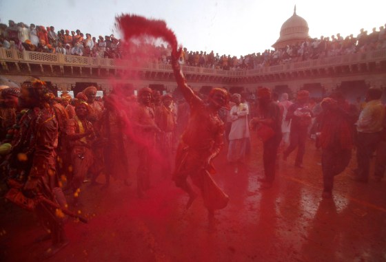 Men throw red colour powder as they celebrate "Lathmar Holi" at village Nandgaon in the northern Indian state of Uttar Pradesh March 3, 2012. In a Holi tradition unique to Nandgaon and Barsana villages, men sing provocative songs to gain the attention of women, who then "beat" them with bamboo sticks called "lathis". Holi, also known as the Festival of Colours, heralds the beginning of spring and is celebrated all over India. REUTERS/Adnan Abidi (INDIA - Tags: SOCIETY RELIGION TPX IMAGES OF THE DAY)