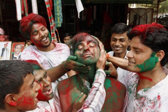 Samajwadi Party supporters smear party flag colored powder on each others' faces as they celebrate the early leads of the party leader Mulayam Singh Yadav outside the party office in Lucknow, India, Tuesday, March 6, 2012. Election officials across five Indian states Tuesday began counting votes in crucial provincial elections that are being seen as a test of strength for the country's ruling Congress party. (AP Photo/Rakesh Kumar Singh)