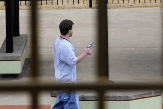 A gunman holds a gun as Tulsa County sheriff's deputies and other law enforcement officers surround him on the plaza in front of the Tulsa County courthouse in Tulsa, Oklahoma, March 7, 2012. The gunman was