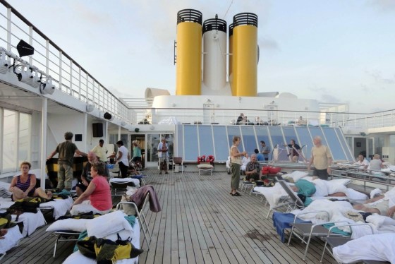 In this image taken on Tuesday, Feb. 28, 2012 by a passenger of the Costa Allegra cruise ship, passengers sit on the deck of the ship. A disabled cruise ship carrying more than 1,000 people docked in the island nation of the Seychelles Thursday after three days at sea without power since a fire broke out in the generator room on Monday. (AP Photo/Eleonor Bradwell)