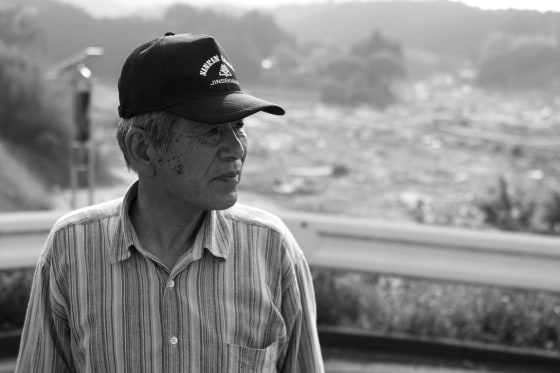 Rice farmer Katsushi Haga looks at the wiped out town of Koizumi, Japan, from a nearby hillside on June 8, 2011.
