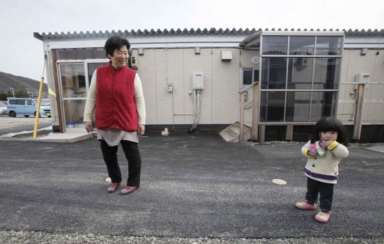 One-year-old girl Rin Yokota, right, is accompanied by her grandmother Tomoko Igari, 63, as they walk in the compound of their temporary housing in Otama village, Fukushima Prefecture, northern Japan, Thursday, March 8, 2012. Nearly one year after the March 11 earthquake and tsunami crippled the Fukushima Dai-ichi nuclear power station, many of the 100,000 people who have been evacuated from the 20-kilometer (12-mile) no-go zone still live in the similar housing complex in Fukushima. (AP Photo/Koji Sasahara)