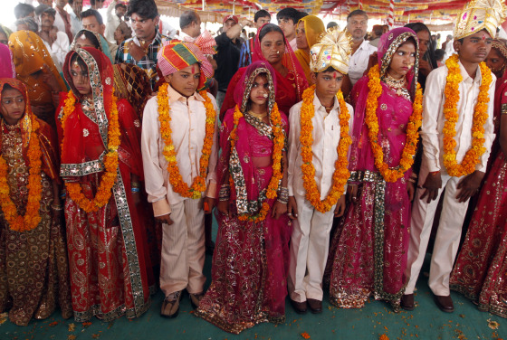 Boys and girls from the Saraniya community wearing garlands pose for pictures after their engagement ceremony at Vadia village in the western Indian state of Gujarat March 11, 2012. The Vadia village in western India hosted a mass wedding and engagement ceremony of 21 girls on Sunday aimed at breaking a tradition of prostitution which has for centuries exploited women of a poor, marginalised and once nomadic community in the region. REUTERS/Amit Dave (INDIA - Tags: SOCIETY)