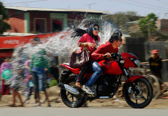 Young Indians splash water on bikers on the last day of Yaoshang, or the Holi festival celebrations, in Imphal, India, Monday, March 12, 2012. Holi, the Hindu festival of colors, also heralds the coming of spring. (AP Photo/Bullu Raj)